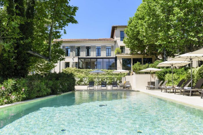 Hôtel élégant avec piscine extérieure, espaces verts et terrasse, parfait pour améliorer rentabilité hôtel et offrir une expérience inoubliable aux clients, sous un ciel bleu clair.