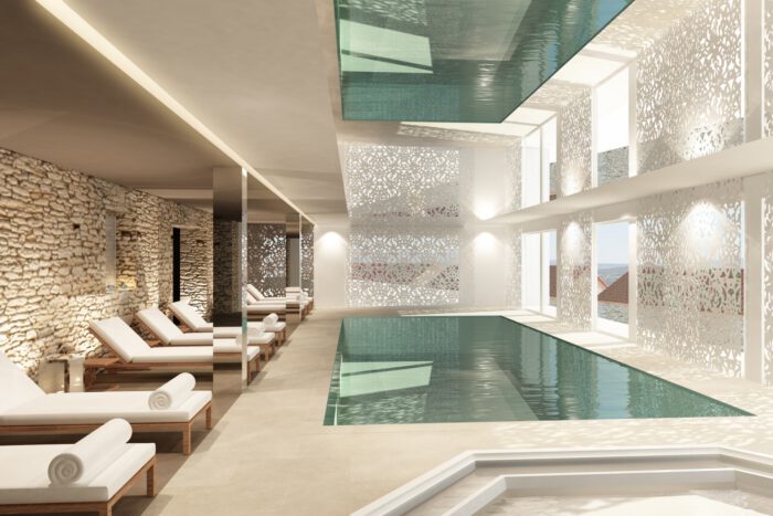 Piscine intérieure élégante d’un hôtel luxueux, idéale pour un audit hôtel, avec chaises longues, décoration moderne et lumière naturelle abondante.