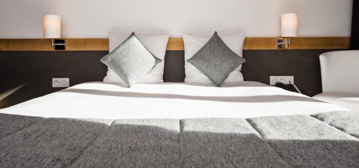 Lit moderne et élégant dans une chambre d’hôtel, idéal pour un audit hôtel, mettant en valeur confort, propreté et décoration contemporaine propice à une expérience client optimale.